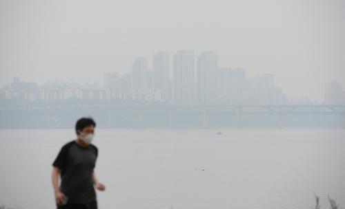 지난 9월 미세먼지로 뿌연 서울 한강변을 한 시민이 마스크를 쓰고 달리고 있다.