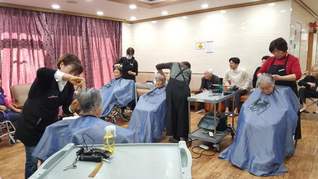 28일 한수원 한울본부 헤어스케치봉사단이 지역 어르신들의 머리를 이발해드리고 있다.