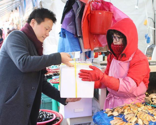 한국동서발전 직원이 울산농수산물도매시장 수산소매동을 찾아 물건을 사고 있다.