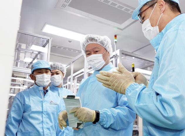 배터리 셀을 든 최태원 회장(가운데)이 김진영 배터리생산기술본부장(오른쪽)으로부터 이에 대한 설명을 듣고 있다. 