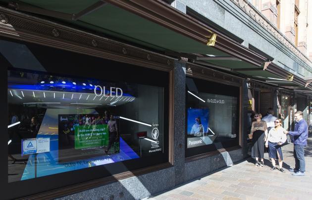 LG디스플레이가 영국 해롯백화점 1층 쇼윈도에 전시한 글로벌업체들의 OLED TV를 방문객들이 관람하고 있다