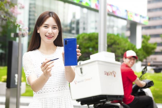 SK텔레콤 홍보모델들이 ‘갤럭시노트10플러스 아우라 블루’ 제품과 공식 온라인몰 배송 서비스인 ‘오늘도착’을 소개하고 있는 모습.