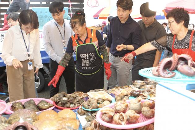 한국동서발전 직원들이 전통시장에서 해산물 을 구매하고 있다.  