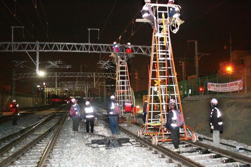 철도건설 현장에서 전차선 기술자들이 이동식 사다리에 올라 작업을 실시하고 있다.