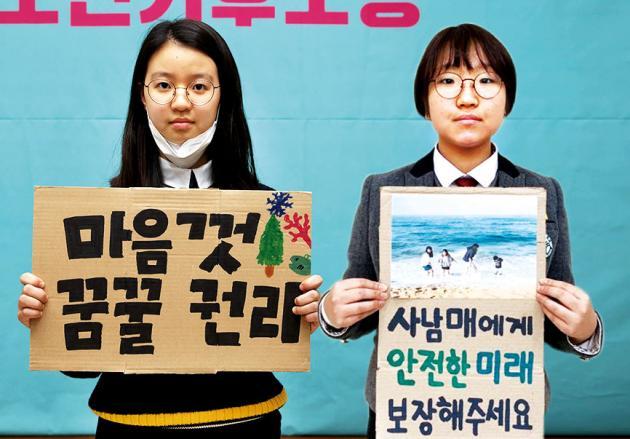 청소년기후소송에서 기후위기 대응을 촉구하는 목소리를 높이는 데 힘을 보태고 있는 김도현(왼쪽), 윤현정 활동가가 피켓을 들고 사진을 찍고 있다.