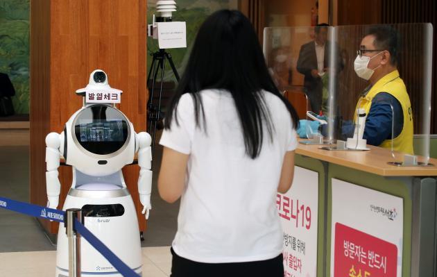 서울 서초구청 입구에서 적외선 카메라와 안면인식 기술이 탑재된 인공지능(AI) 로봇이 구청 방문객들의 체온 측정과 마스크 착용 여부를 확인하고 있다. 제공:연합뉴스