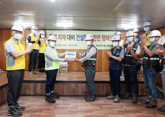 김세용 SH공사 사장(왼쪽 형광색 조끼)이 위례택지개발지구 5단지 건설현장에 폭염응급키트와 이온음료를 제공하고 있다. 
 
