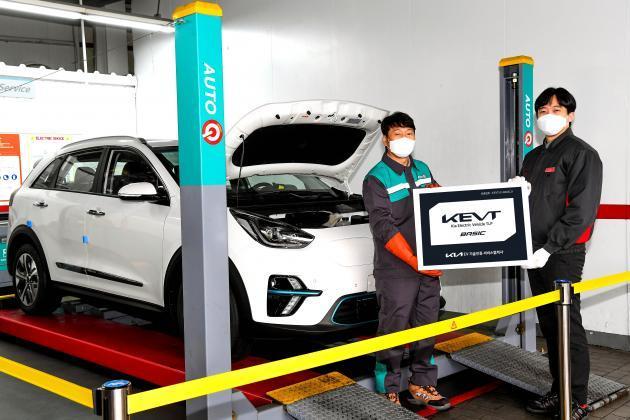 기아 오토큐 정비 엔지니어가 ‘KEVT 베이직’ 인증 현판을 선보이고 있다. 이 인증 현판이 있는 오토큐에서는 전문적인 전기차 정비를 받을 수 있다.