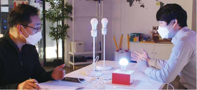 정찬형 레드밴스 과장(오른쪽)이 본지 윤정일 기자에게 첫 와이파이 기반 LED 스마트램프 신제품의 특징과 장점에 대해 설명하고 있다. 