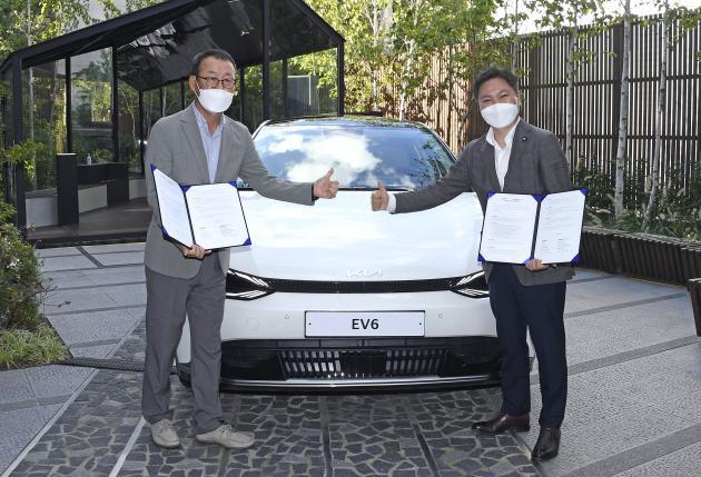 기아 판매사업부장 이한응 전무(왼쪽)와 오영현 휴맥스 모빌리티 공동대표가 업무협약 후 기아 전기차 EV6 앞에서 기념사진을 찍고 있다.