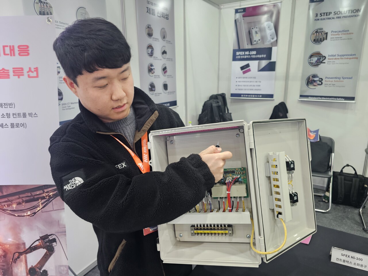 스펙스테크 관계자가 전기박스 화재 자동 소화용구인 ‘SFEX Hi-100’에 라이터 불꽃을 대서 자동으로 소화되는 상황을 연출해 보이고 있다.[사진=윤정일 기자]